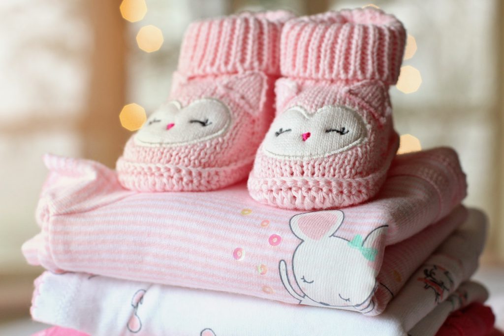 pink baby socks with patch placed on top of folded baby clothes