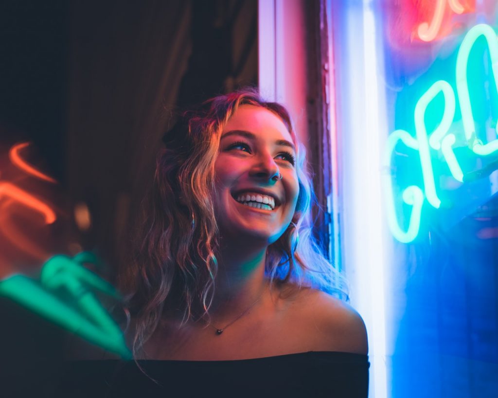 smiling woman wearing a nose piercing and black off shoulder top