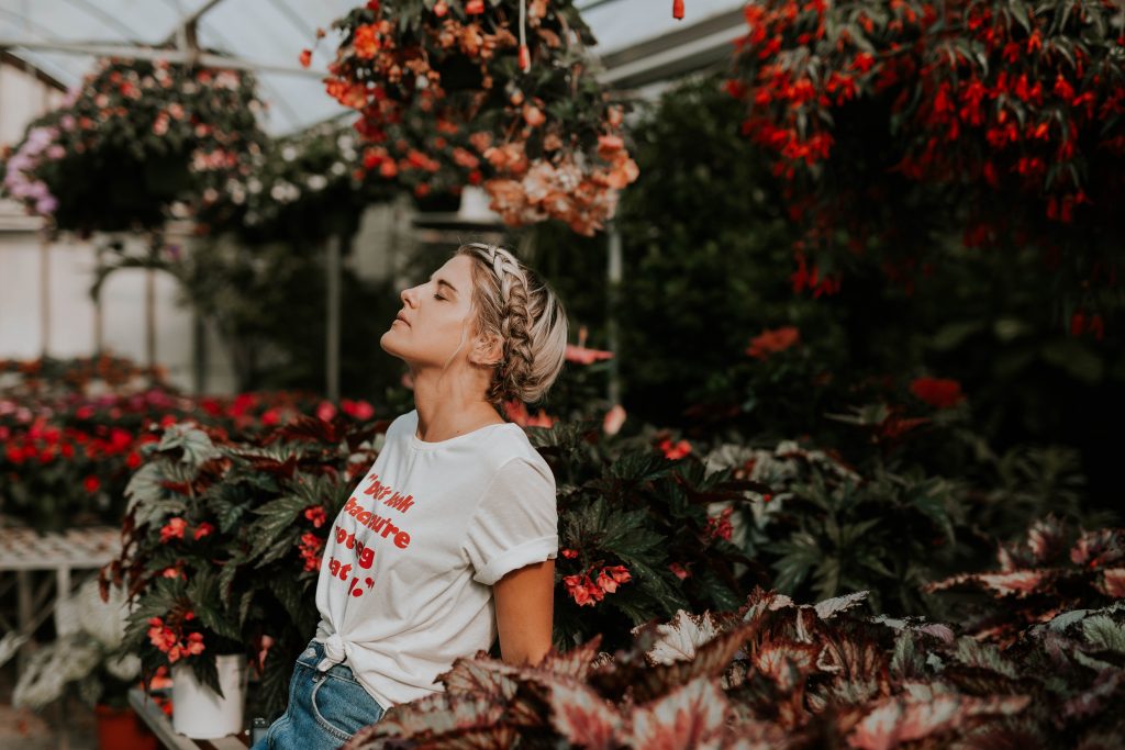 Woman in greenhouse wearing white shirt with knot